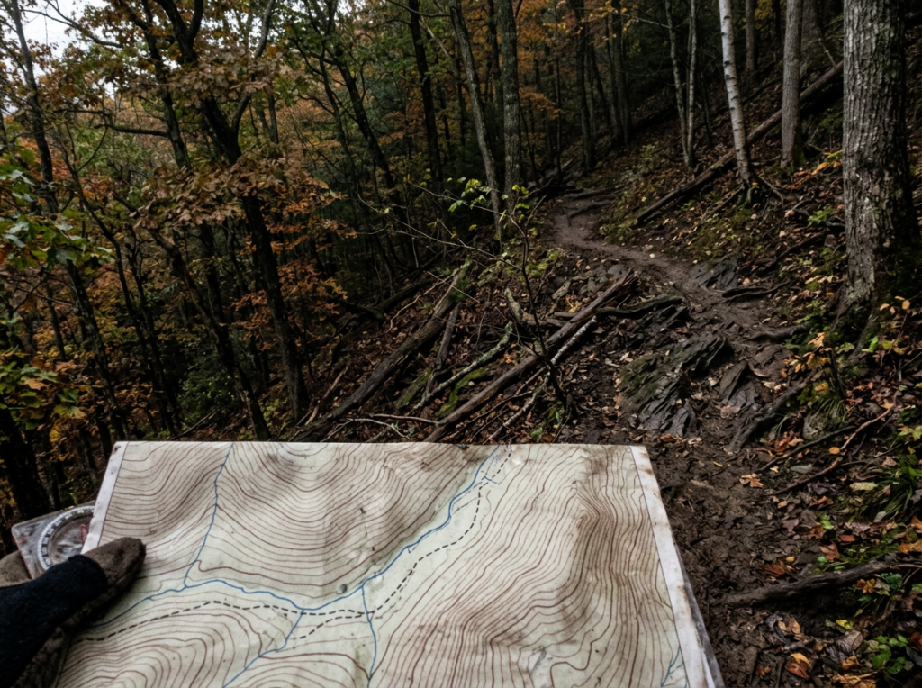 Topographic map held on a rocky autumn forest trail